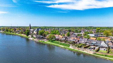 Hollanda 'nın tipik köyünün insansız hava aracı görüntüsü, Hollanda' nın Limburg eyaleti Meuse nehri yakınlarındaki geleneksel evleri ve kilisesi ile huzurlu kırsal alan.