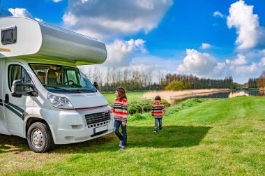 Karavanın yakınındaki çocuklar oyun oynuyor ve eğleniyor, aile seyahatleri karavanda tatilde kamp yapıyor.