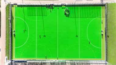 Hokey sahası ve hava aracı manzaralı spor parkı, Hollanda 'da çim hokeyi, spor ve spor altyapı tesisleri oynayan insanlar.
