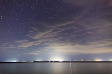 Göldeki yıldızlı gökyüzü. Gece manzarası. Bulutlu gökyüzü. Kırgızistan