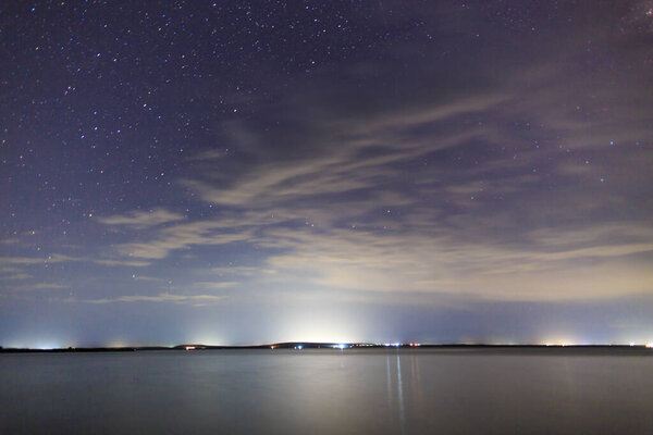 Starry sky on the lake. Night landscape. Sky with clouds. Kyrgyzstan