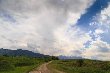 Güzel bahar ve yaz manzarası. Yeşil tepelerin arasındaki dağ yolu. yemyeşil tepeler, yüksek dağlar.