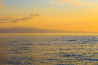 Mavi ve turuncu berrak su dokusu. Okyanusun ve denizin arkaplanı güneşle aydınlanıyor..