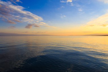 Denizde renkli bir gün batımı. Turuncu güneş ışınlarında dağ gölü. Kırgızistan, Issyk-Kul Gölü. doğal arkaplan