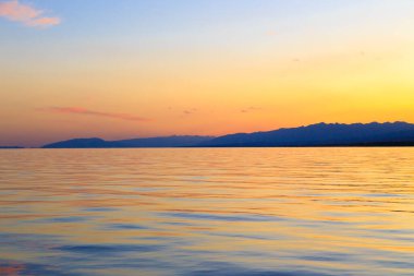 Mavi ve turuncu berrak su dokusu. Okyanusun ve denizin arkaplanı güneşle aydınlanıyor..