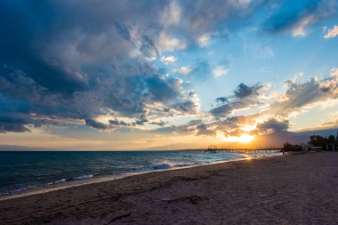 Denizde renkli bir gün batımı. Turuncu güneş ışınlarında dağ gölü. Kırgızistan, Issyk-Kul Gölü. Doğal arka plan. Peyzaj
