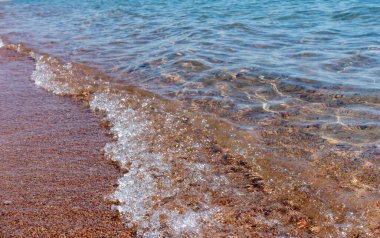 Temiz şeffaf su, kumsalda el salla. Kıyı şeridi. Kırgızistan, Issyk-Kul Gölü. Doğal arka plan. Peyzaj