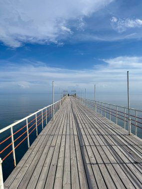 Wooden pier on the seashore. Mountains and clear water. Lake Issyk-Kul clipart