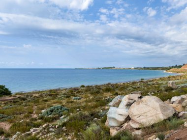 Issyk-Kul 'un kayalık kıyı manzarası. Çalı bitki örtüsü ve mavi gökyüzü. Kırgızistan 'da turistler ve gezginler için doğal bir yer