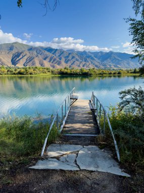 Issyk-Kul Gölü 'nde dağları gören ahşap bir iskele. Rahatlamak ve Kırgızistan 'ın doğal manzaralarının tadını çıkarmak için güzel bir yer..