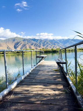 Issyk-Kul Gölü 'nde dağları gören ahşap bir iskele. Rahatlamak ve Kırgızistan 'ın doğal manzaralarının tadını çıkarmak için güzel bir yer..