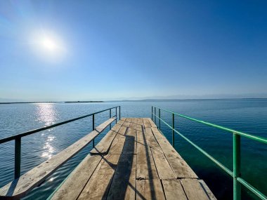 Issyk-Kul Gölü 'nde dağları gören ahşap bir iskele. Rahatlamak ve Kırgızistan 'ın doğal manzaralarının tadını çıkarmak için güzel bir yer..