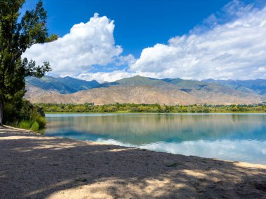 Arka planda görkemli dağlarla Issyk-Kul gölünün sakin su yüzeyi. Kırgızistan 'ın güzel doğal manzarası.