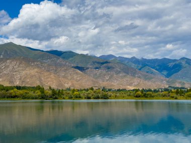 Arka planda görkemli dağlarla Issyk-Kul gölünün sakin su yüzeyi. Kırgızistan 'ın güzel doğal manzarası.