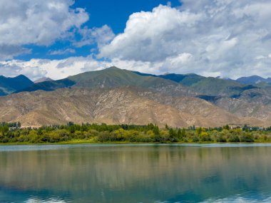 Arka planda görkemli dağlarla Issyk-Kul gölünün sakin su yüzeyi. Kırgızistan 'ın güzel doğal manzarası.