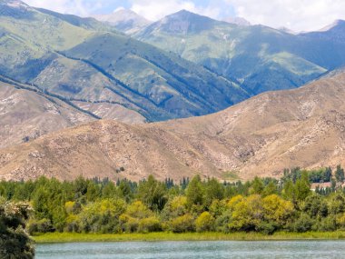 Arka planda görkemli dağlarla Issyk-Kul gölünün sakin su yüzeyi. Kırgızistan 'ın güzel doğal manzarası.