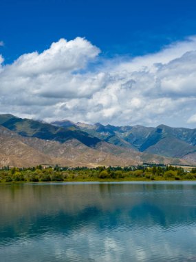 Arka planda görkemli dağlarla Issyk-Kul gölünün sakin su yüzeyi. Kırgızistan 'ın güzel doğal manzarası.