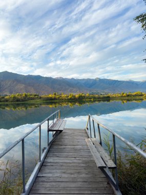 Issyk-Kul Gölü 'nde dağları gören ahşap bir iskele. Rahatlamak ve Kırgızistan 'ın doğal manzaralarının tadını çıkarmak için güzel bir yer..