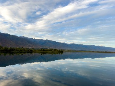 Yeşil vadiler ve görkemli dağlarla çevrili sessiz bir dağ gölü Issyk-Kul. Kırgızistan 'da turizm ve huzurlu dinlenme için mükemmel bir yer.