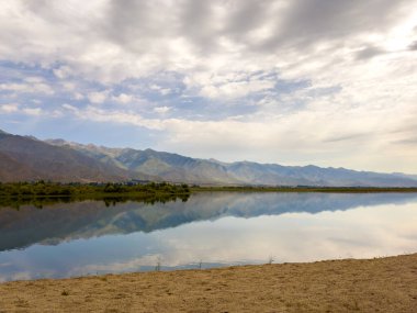 Yeşil vadiler ve görkemli dağlarla çevrili sessiz bir dağ gölü Issyk-Kul. Kırgızistan 'da turizm ve huzurlu dinlenme için mükemmel bir yer.