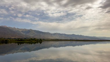 Yeşil vadiler ve görkemli dağlarla çevrili sessiz bir dağ gölü Issyk-Kul. Kırgızistan 'da turizm ve huzurlu dinlenme için mükemmel bir yer.