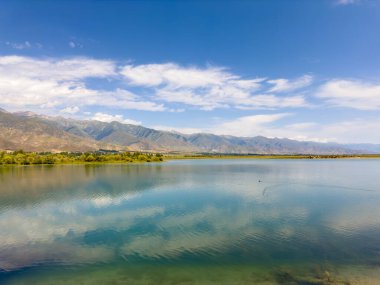 Yeşil vadiler ve görkemli dağlarla çevrili sessiz bir dağ gölü Issyk-Kul. Kırgızistan 'da turizm ve huzurlu dinlenme için mükemmel bir yer.