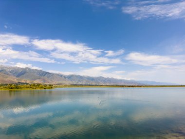 Yeşil vadiler ve görkemli dağlarla çevrili sessiz bir dağ gölü Issyk-Kul. Kırgızistan 'da turizm ve huzurlu dinlenme için mükemmel bir yer.