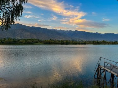 Arka planda görkemli dağlarla Issyk-Kul gölünün sakin su yüzeyi. Kırgızistan 'ın güzel doğal manzarası.