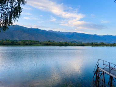 Yeşil vadiler ve görkemli dağlarla çevrili sessiz bir dağ gölü Issyk-Kul. Kırgızistan 'da turizm ve huzurlu dinlenme için mükemmel bir yer.