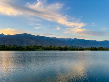 Arka planda görkemli dağlarla Issyk-Kul gölünün sakin su yüzeyi. Kırgızistan 'ın güzel doğal manzarası.