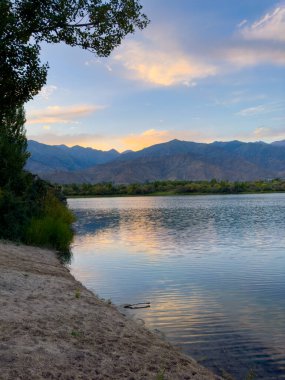 Yeşil vadiler ve görkemli dağlarla çevrili sessiz bir dağ gölü Issyk-Kul. Kırgızistan 'da turizm ve huzurlu dinlenme için mükemmel bir yer.