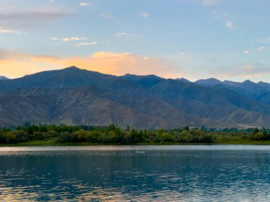 Sessiz dağ gölü, akşam güneşi, Kırgızistan. Gölde durgun su ve dağ yansıması.