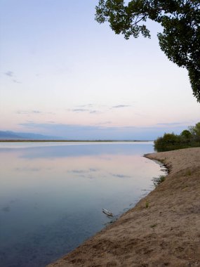Sessiz dağ gölü, akşam güneşi, Kırgızistan. Gölde durgun su ve dağ yansıması.