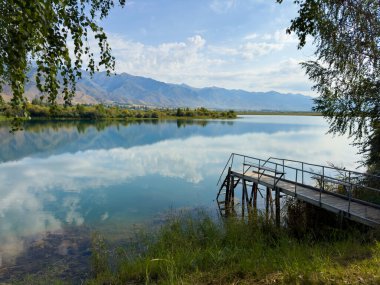 Issyk-Kul Gölü 'nde dağları gören ahşap bir iskele. Rahatlamak ve Kırgızistan 'ın doğal manzaralarının tadını çıkarmak için güzel bir yer..