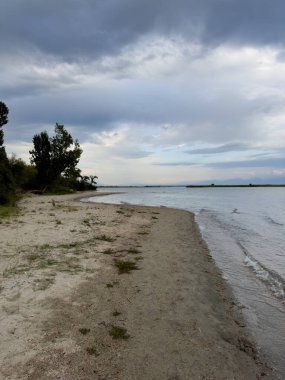 Issyk-Kul gölünün sakin suları dramatik bulutları ve dağları yansıtır. Kırgızistan 'daki doğal bir vahada sessizlik ve sükunet..