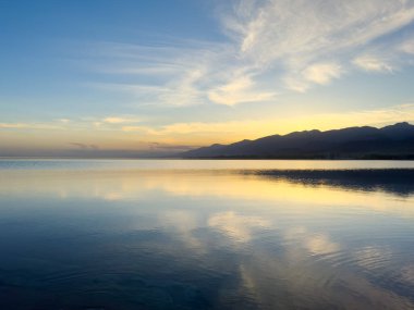 Sessiz dağ gölü, akşam güneşi, Kırgızistan. Gölde durgun su ve dağ yansıması