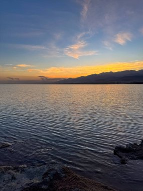 Sessiz dağ gölü, akşam güneşi, Kırgızistan. Gölde durgun su ve dağ yansıması