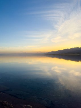 Sessiz dağ gölü, akşam güneşi, Kırgızistan. Gölde durgun su ve dağ yansıması