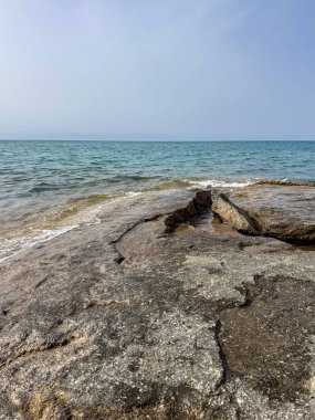 Uçsuz bucaksız gökyüzünün altında Issyk-Kul 'un kayalık kıyısı ve berrak suyu.