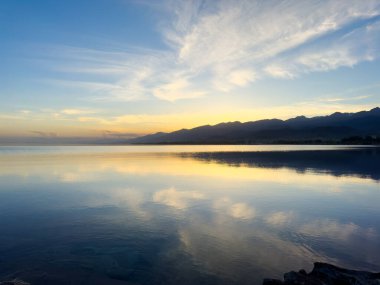 Sessiz dağ gölü, akşam güneşi, Kırgızistan. Gölde durgun su ve dağ yansıması