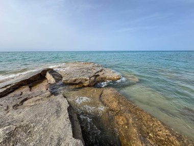 Uçsuz bucaksız gökyüzünün altında Issyk-Kul 'un kayalık kıyısı ve berrak suyu.
