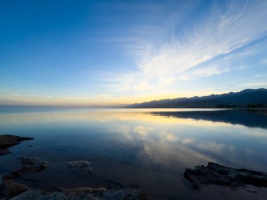 Sessiz dağ gölü, akşam güneşi, Kırgızistan. Gölde durgun su ve dağ yansıması