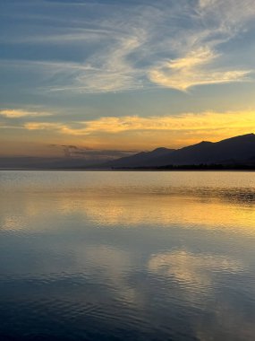 Sessiz dağ gölü, akşam güneşi, Kırgızistan. Gölde durgun su ve dağ yansıması