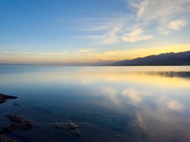 Sessiz dağ gölü, akşam güneşi, Kırgızistan. Gölde durgun su ve dağ yansıması