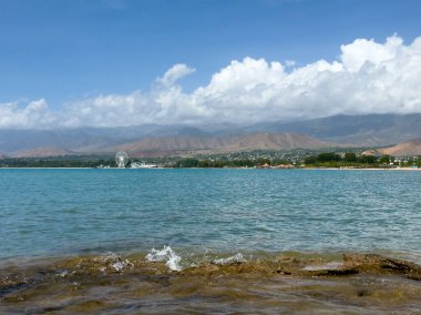 Uçsuz bucaksız gökyüzünün altında Issyk-Kul 'un kayalık kıyısı ve berrak suyu.
