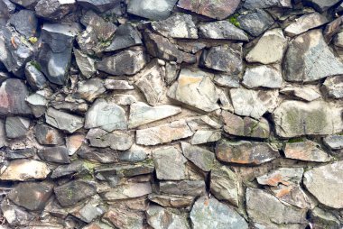 Yosun ve çatlaklardan oluşmuş taştan yapılmış eski bir duvarın dokusu. Doğal taş arkaplan