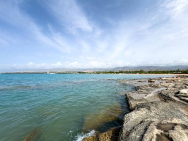 Uçsuz bucaksız gökyüzünün altında Issyk-Kul 'un kayalık kıyısı ve berrak suyu.