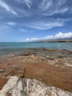Uçsuz bucaksız gökyüzünün altında Issyk-Kul 'un kayalık kıyısı ve berrak suyu.