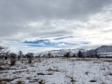 Kırgızistan 'da dağları kaplayan kar bulutlu kış gökyüzü altında huzurlu kırsal alan.