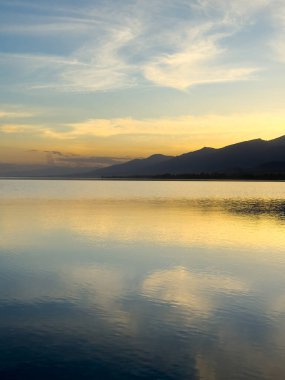 Sessiz dağ gölü, akşam güneşi, Kırgızistan. Gölde durgun su ve dağ yansıması